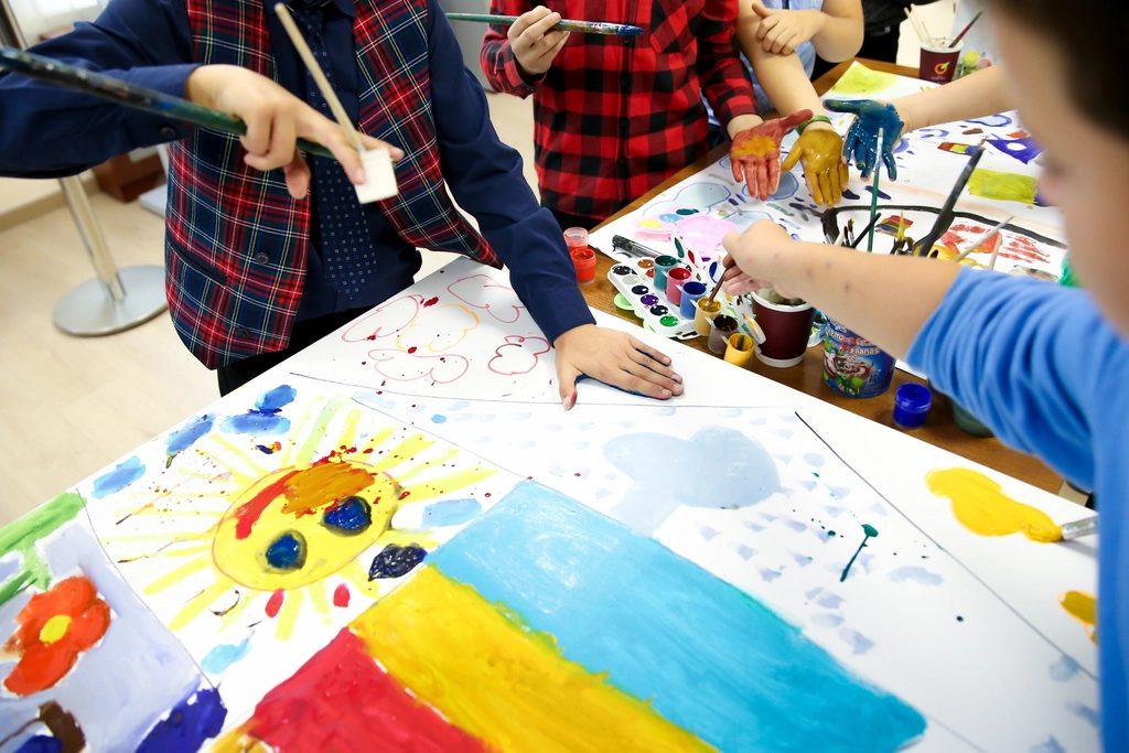 大きな紙に絵の具で絵を描く子どもたちの手元